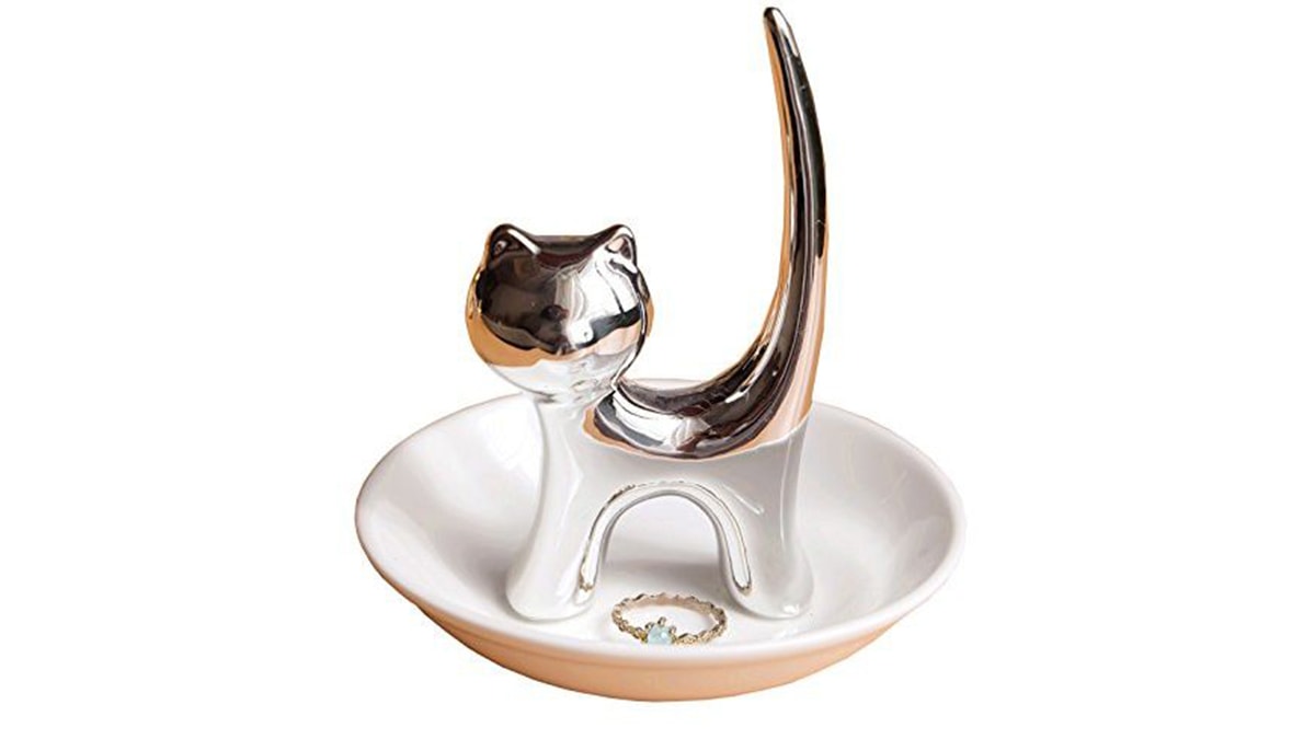 A metal cat ring holder in a with a ring kept beside it. 