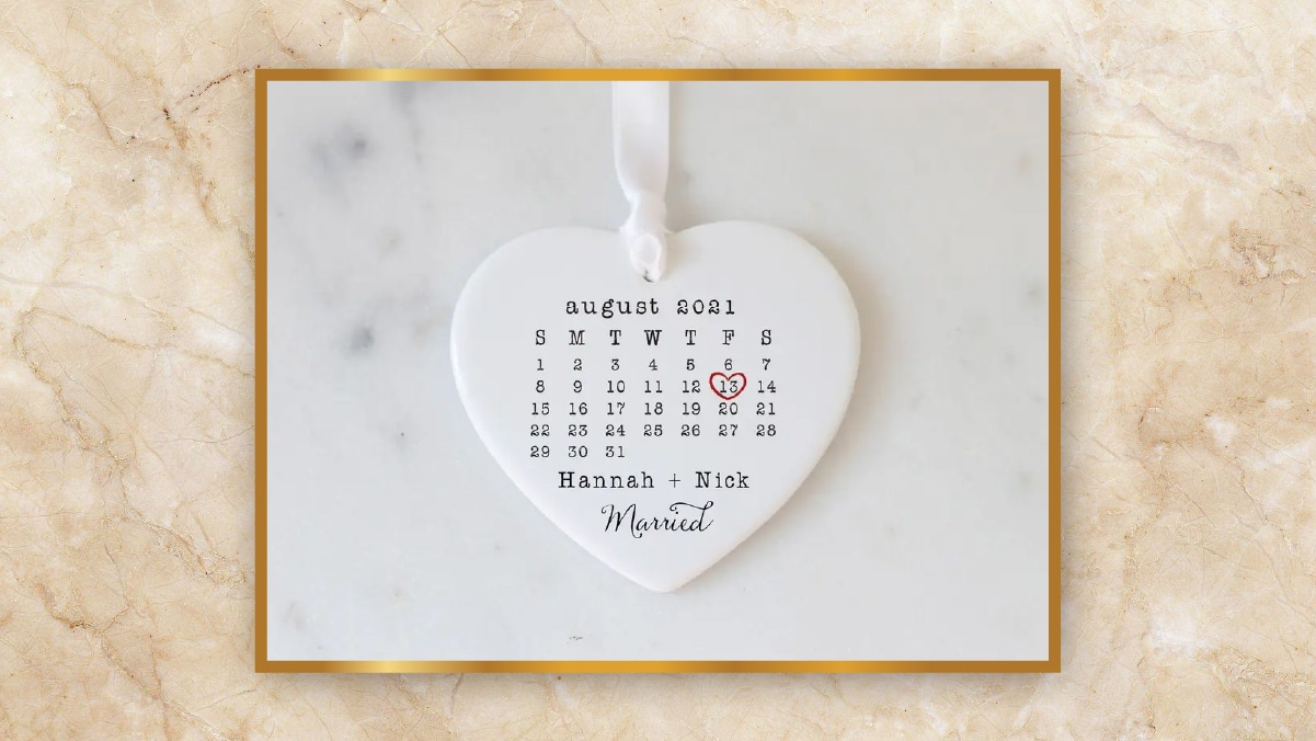 A white heart shaped august moth calendar with 13th marked in red heart kept on a white background as personalized wedding gifts. 