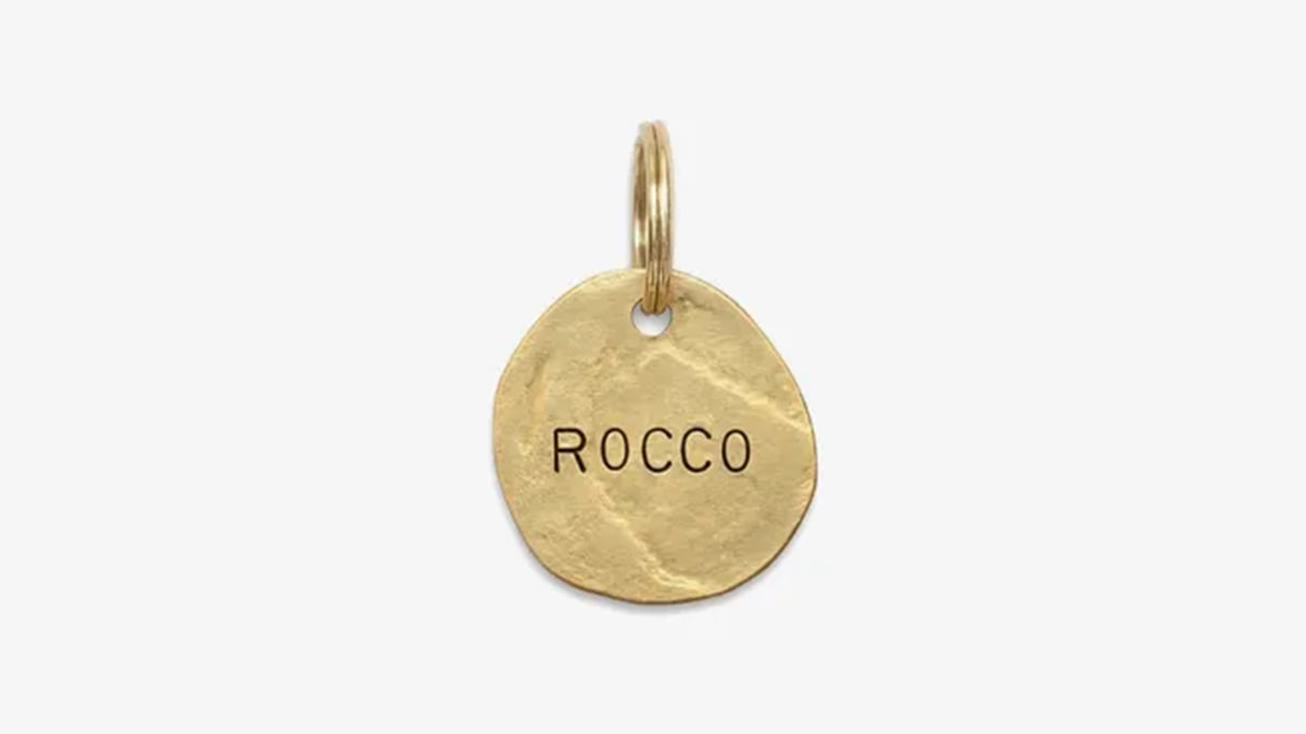 A golden colored pet stamp with rocco written on it in a white background. 