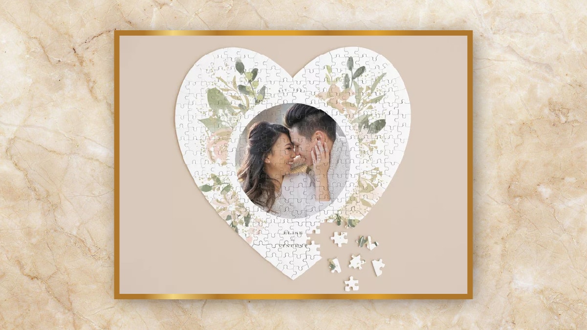 A heart shaped puzzle art with the couple in the center kept in a light brown background as a personalized wedding gifts. 