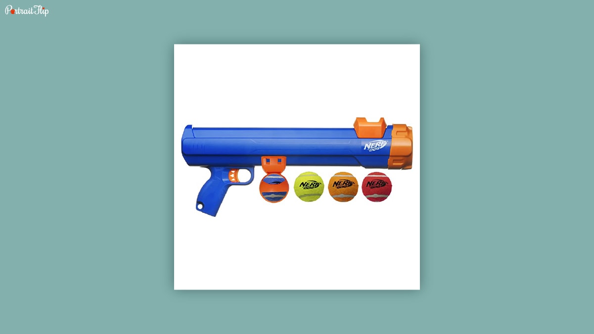 A blue and orange colored nerf gun with 3 different colored tennis balls beneath it on a white background.