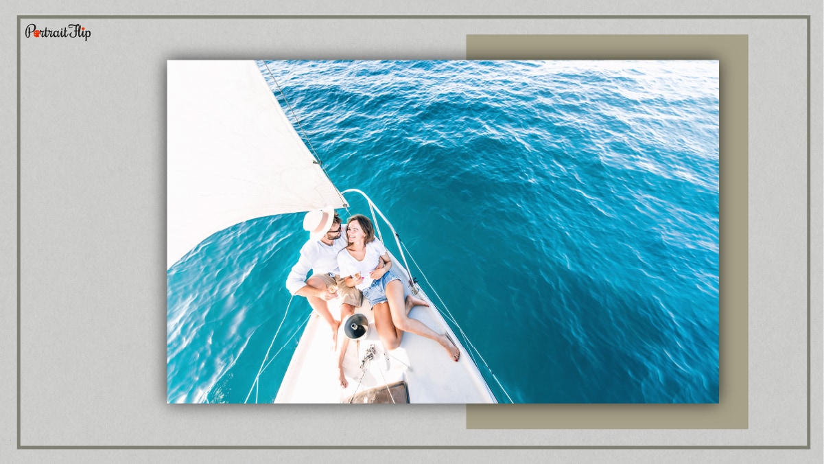 A couple snuggling on a yacht. They are amid ocean and are drinking in a corner of yacht. 