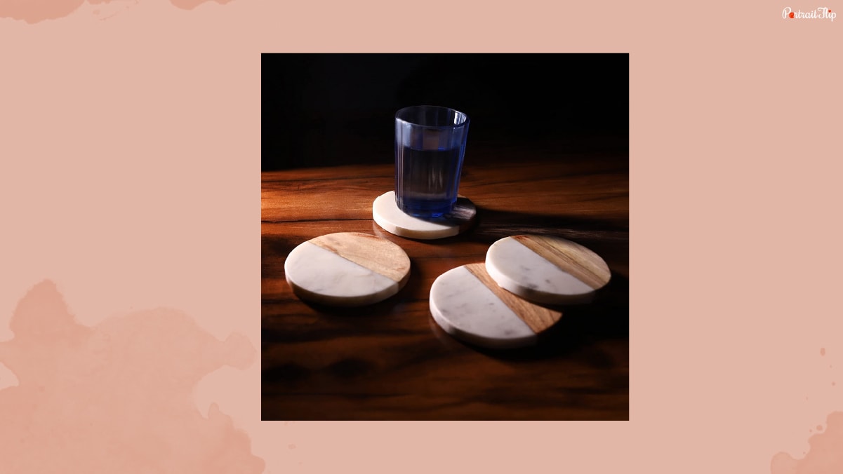 Four coaster placed on the wooden table with a glass of water.