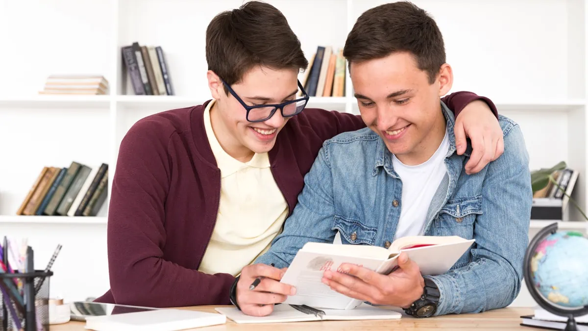 Two gay men smiling while looking towards the planner book in their hand as a gifts for gay men.