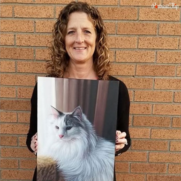 Picture of a woman holding cat portraits in her hands