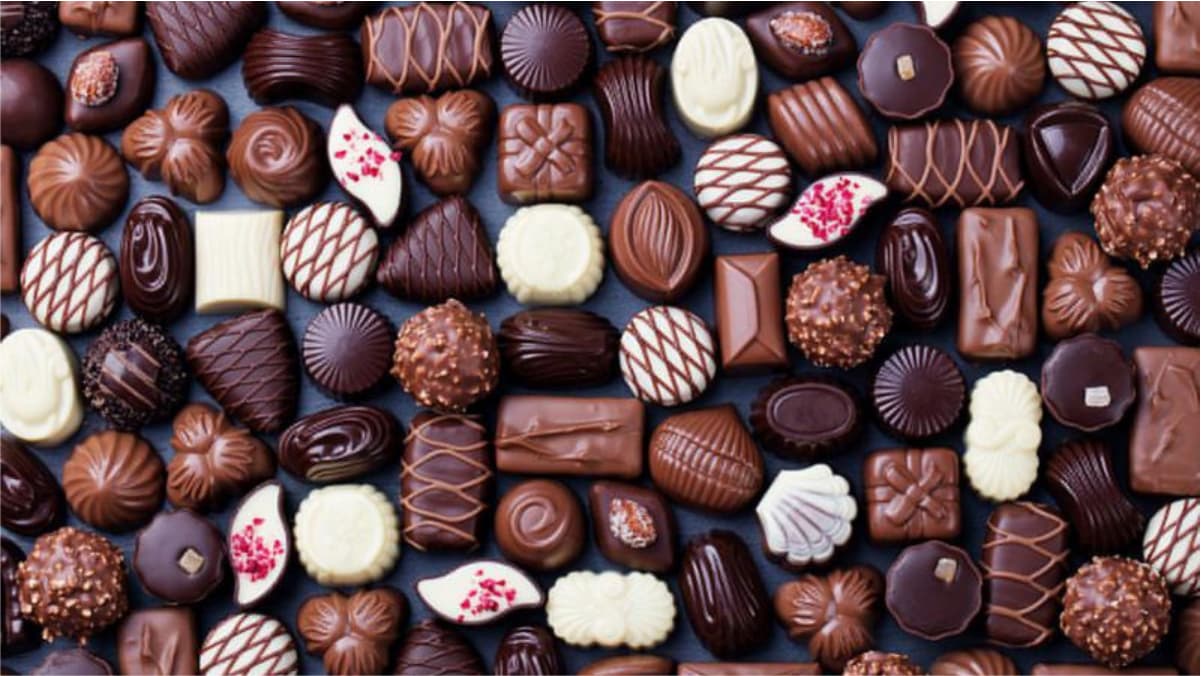 Some delicious chocolates in different shapes are placed on a brown background. 