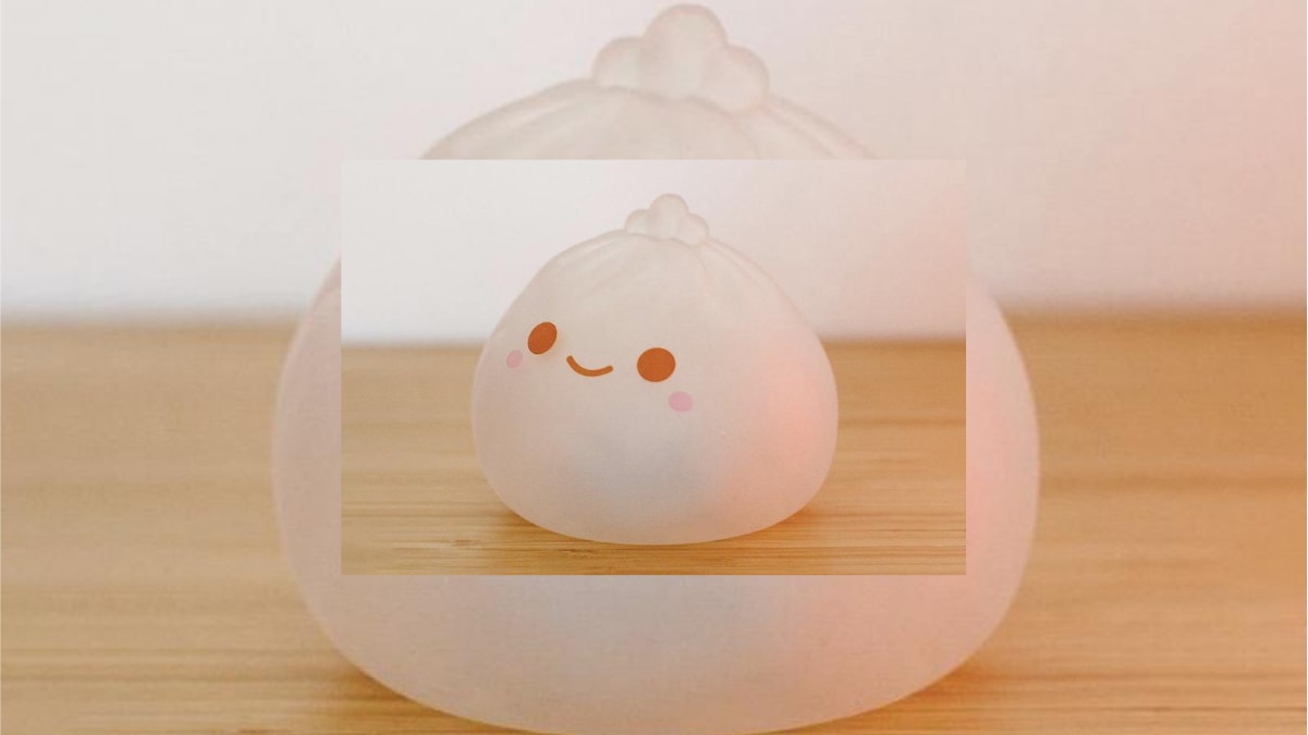 A cute dumpling speaker is placed on the brown plain surface. 