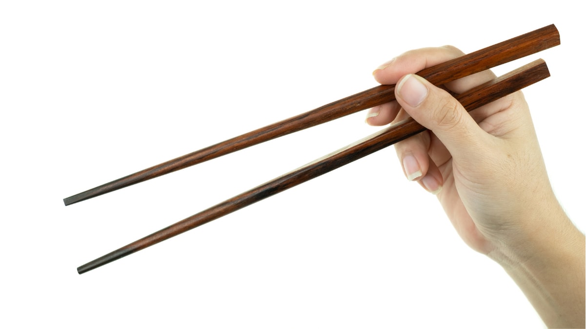 A girl is showing how to hold chopsticks. 