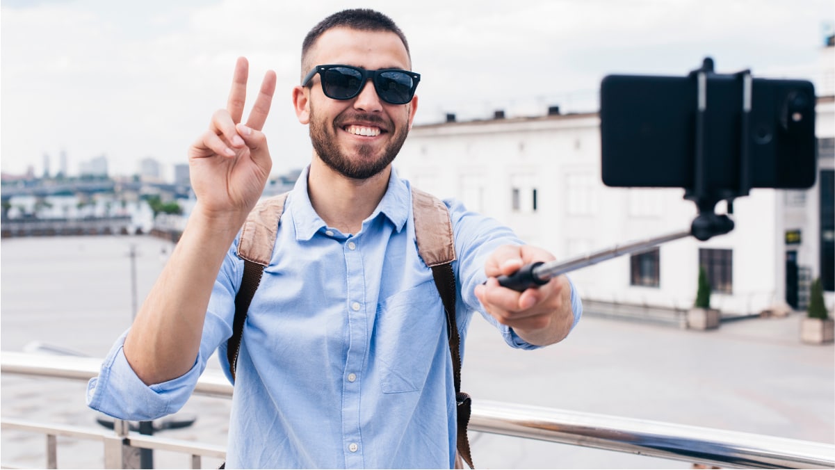 A man showing victory sign while taking a selfie with the help of selfie stand