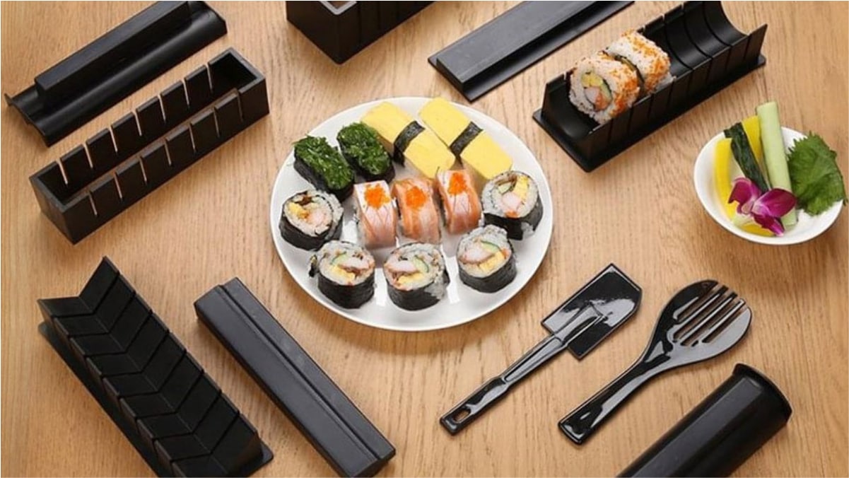Sushi making kit and some delicious Sushi is being served on a white plate placed on the wooden surface. 