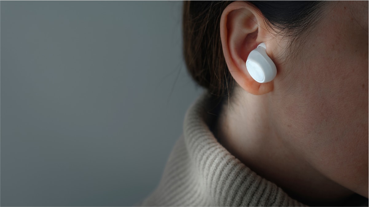 A close-up shot of a woman wearing a wireless earphone. 