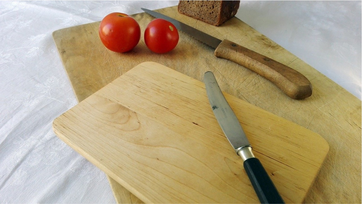Two top-quality bread boards with some tomatoes and knives on them.