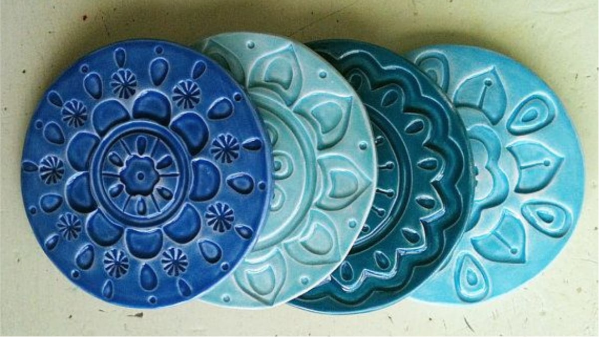 A bunch of beautiful handmade coasters are placed on the green and plain background.
