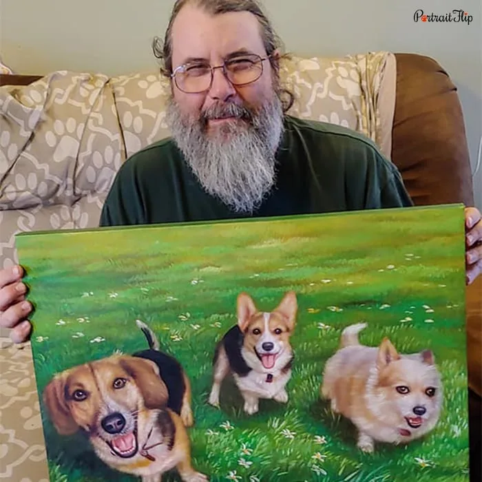 Picture of man holding dog portraits where three dogs are placed next to each other