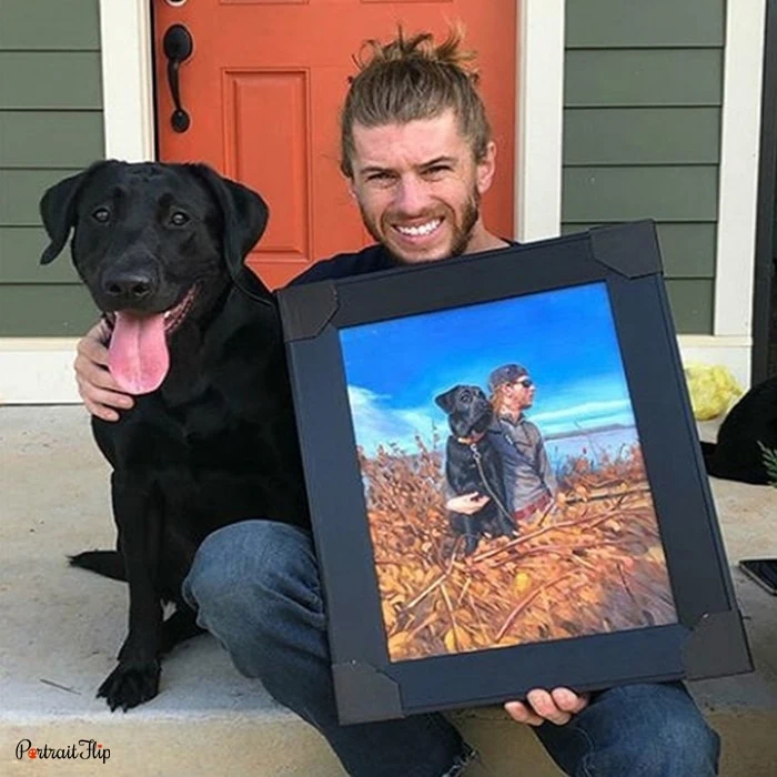 Picture of a man holding dog portraits with his dog beside him