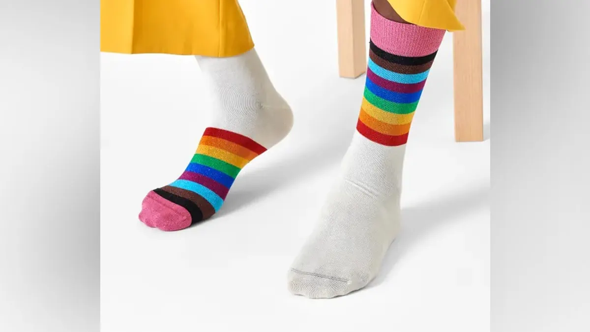 Close up shot of legs wearing rainbow print pair of socks as a gifts for gay men.