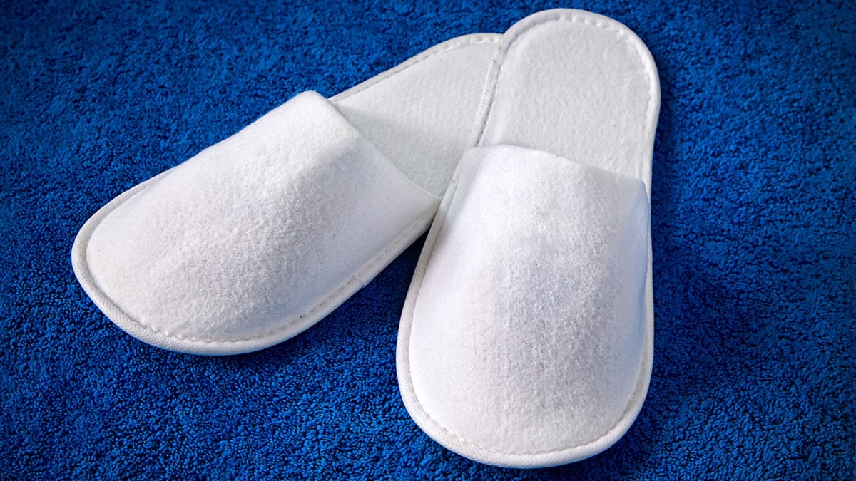 White comfy slippers lying on blue rug