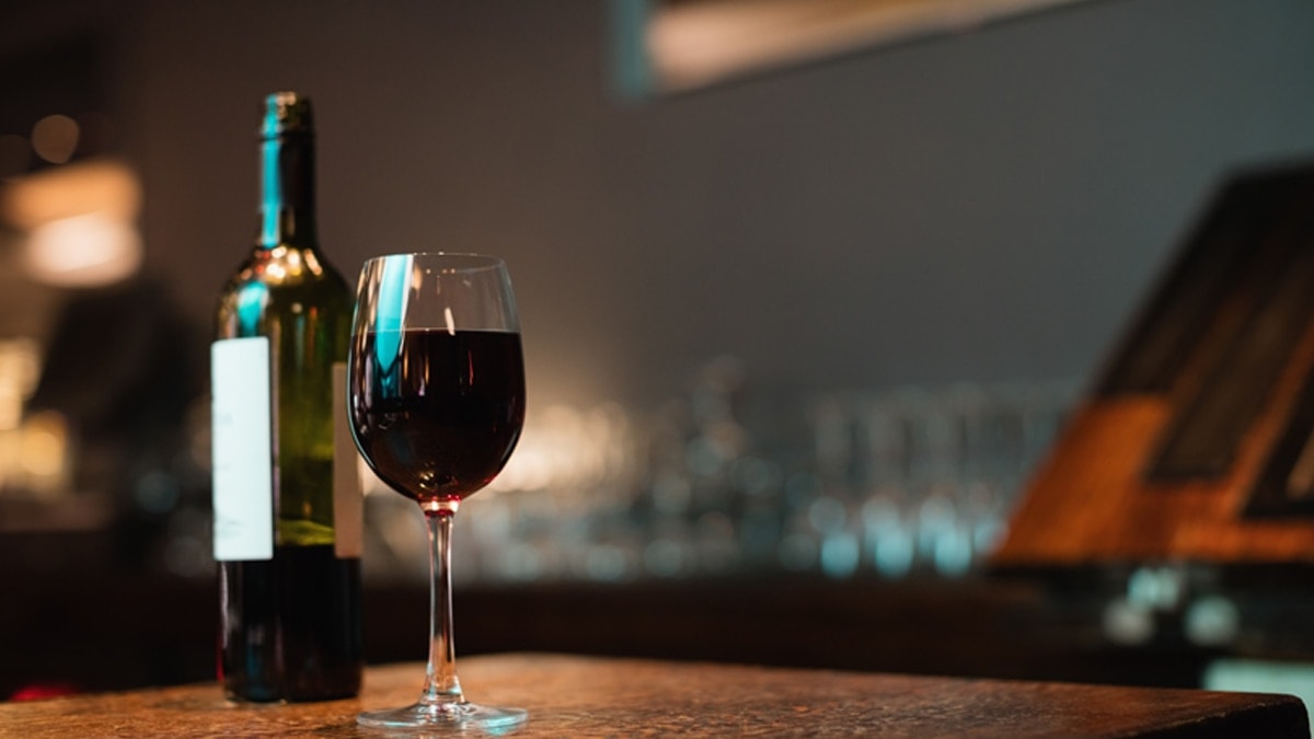 Glass of red wine and bottle on bar counter