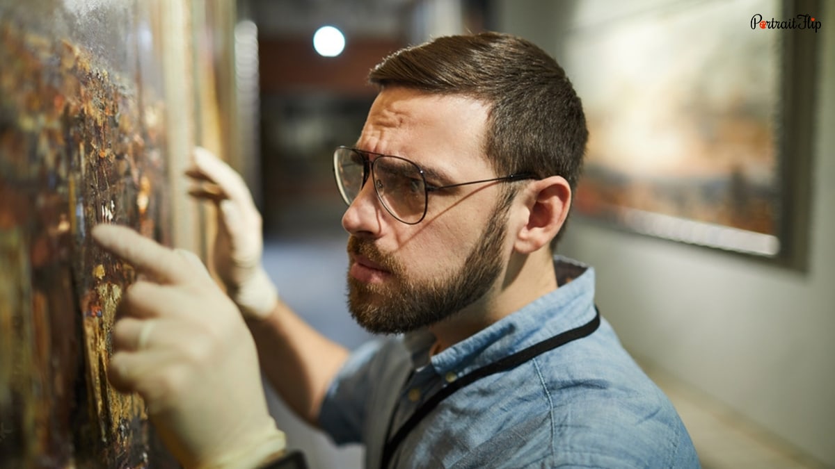 A man focused on a painting and closely inspecting it. 