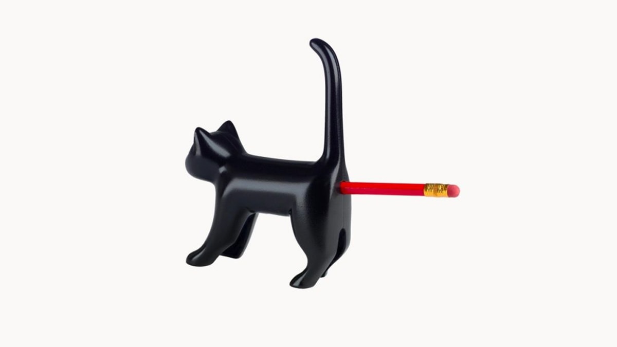 A cat shaped pencil sharpener with a pencil infused in it in a white background. 