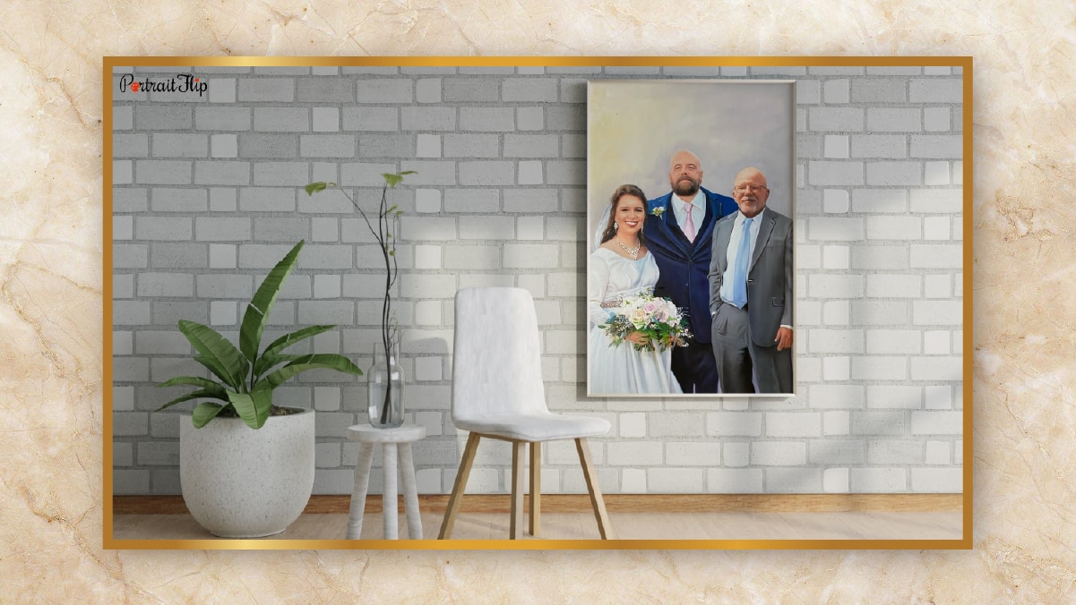 A portrait of 2 men and a women in bridal dress holding flowers in her hand hung on a grey brick wall with a white chair kept beside it as personalized wedding gifts. 