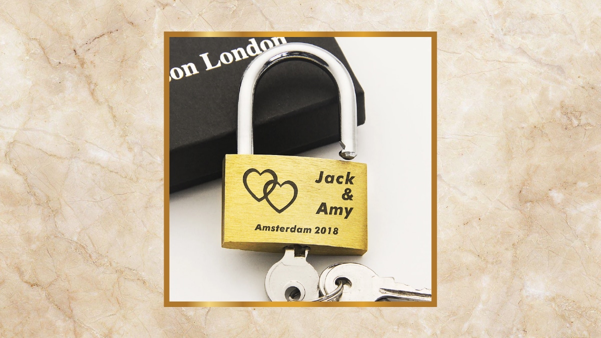 A golden padlock with Jack and Amy written on it kept on a white background. 