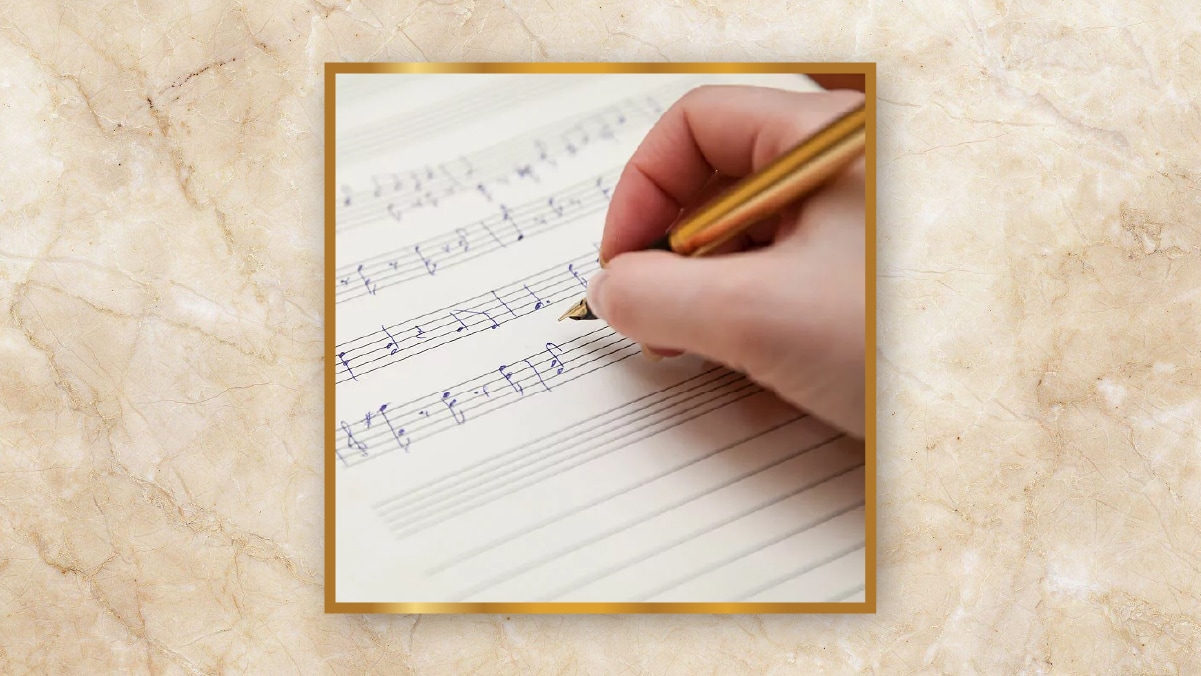 A hand holding a golden pen writing musical notes written on a page as personalized wedding gifts. 