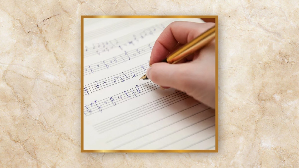 A hand holding a golden pen writing musical notes written on a page as personalized wedding gifts.