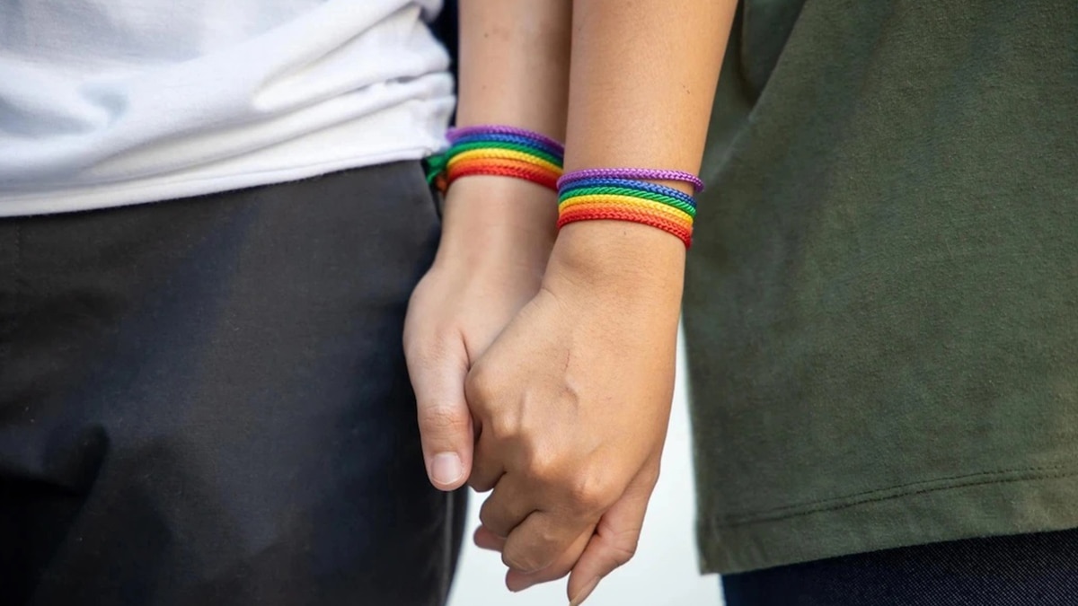 Close up shot of two hands holding, wearing pride band on their wrist as a gifts for gay men.