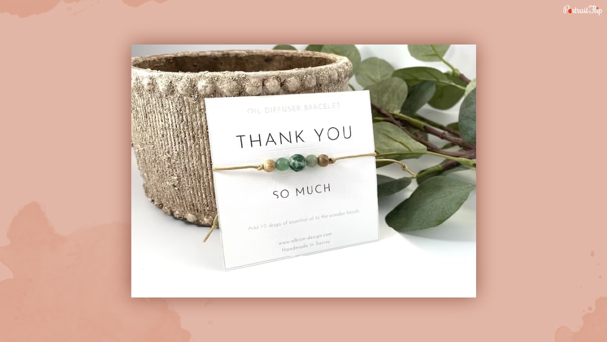 A bracelet placed against a wooden vase that could be one of the thank-you gifts for women.
