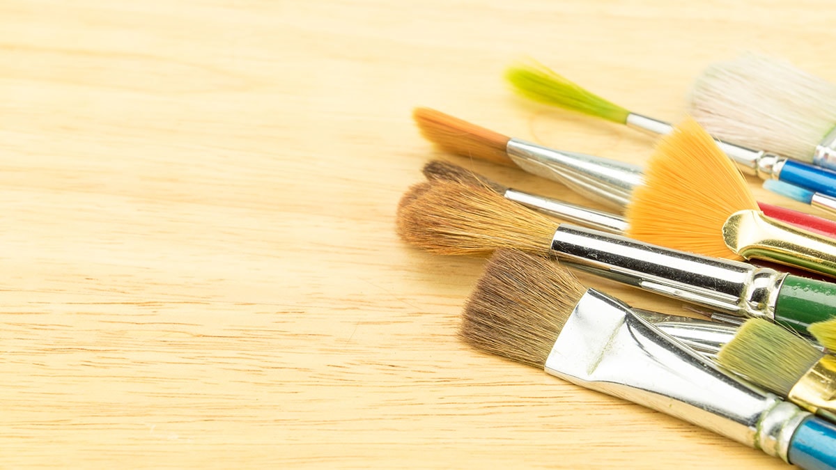 Sets of brushes laying on a wooden slab. 