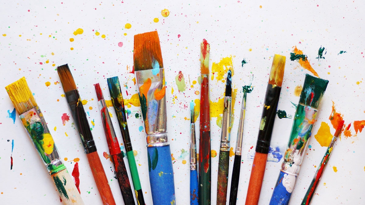 Brushes dipped in paint and arranged in a uniform manner. 
