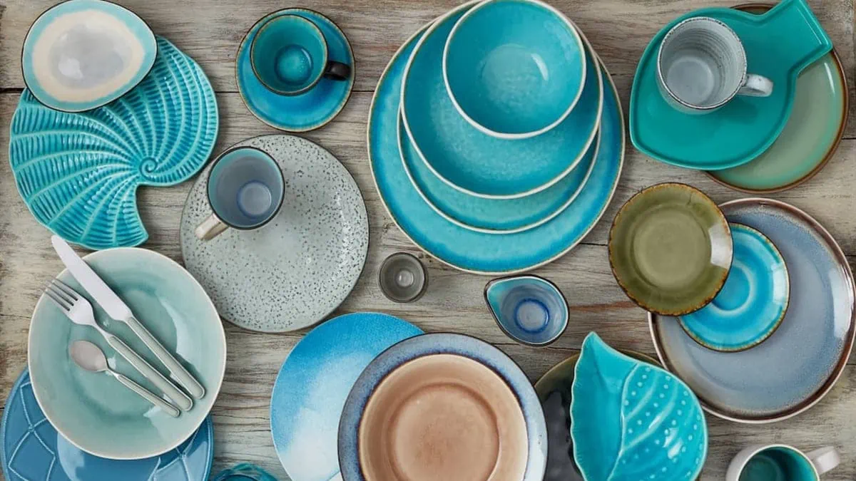 Handmade ceramic plates in beautiful shades of blue placed on a wooden table