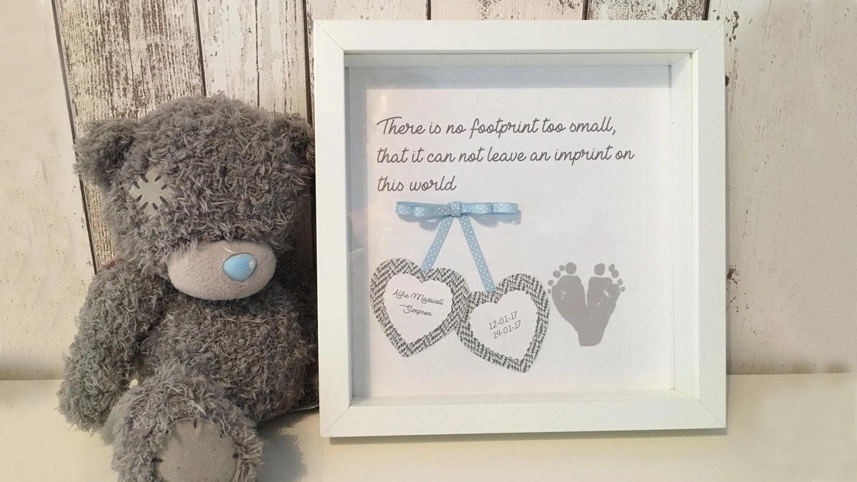 An image of a teddy bear next to a framed photo of a baby's legs with a quote.