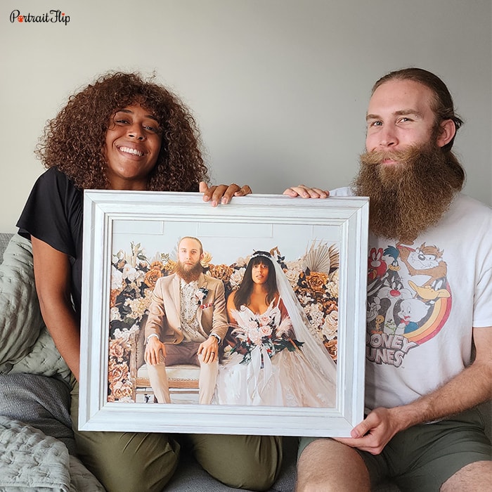 Picture of a couple holding anniversary portraits while sitting on a couch