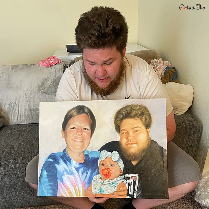 Picture of a man holding baby portraits in his hand, which include him with a baby and an old woman