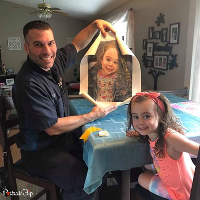 Picture of a man sitting at the dinner table with a girl holding baby portraits that include the same girl