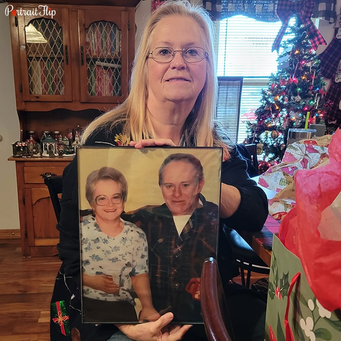 Picture of an old lady holding couple portraits that feature an old woman and man