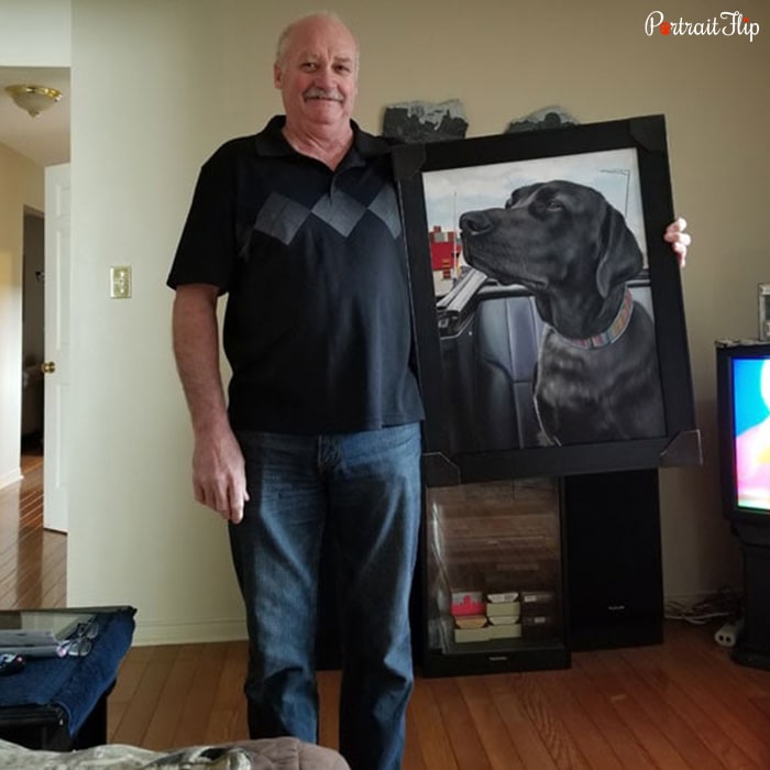 Picture of an old man holding a painting that shows a close-up of dog’s face