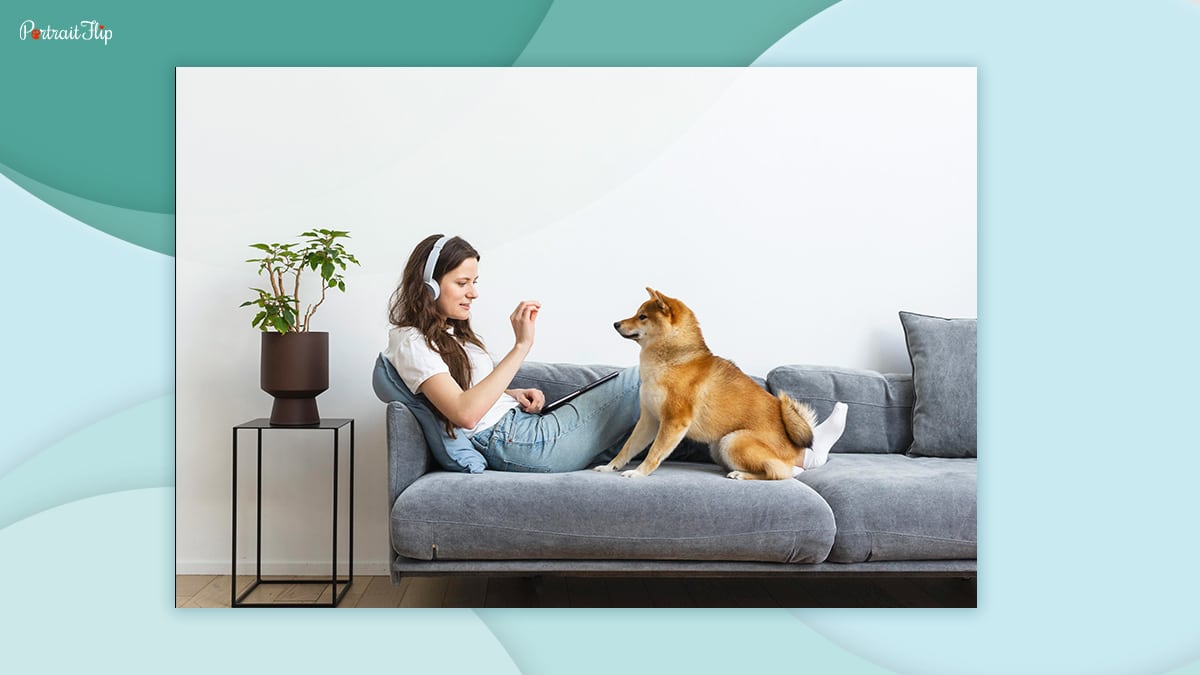 A woman can be seen resting on a couch along with her dog