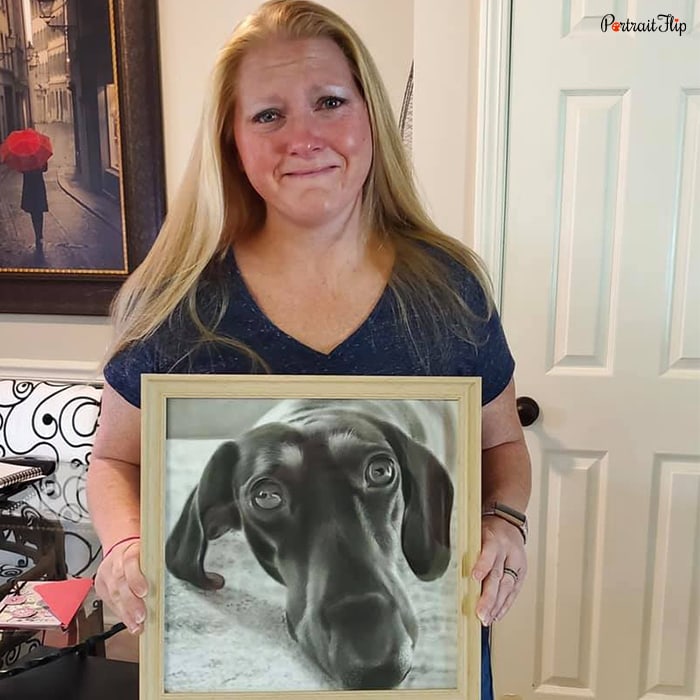 Picture of a woman holding memorial portraits of a dog in her hand