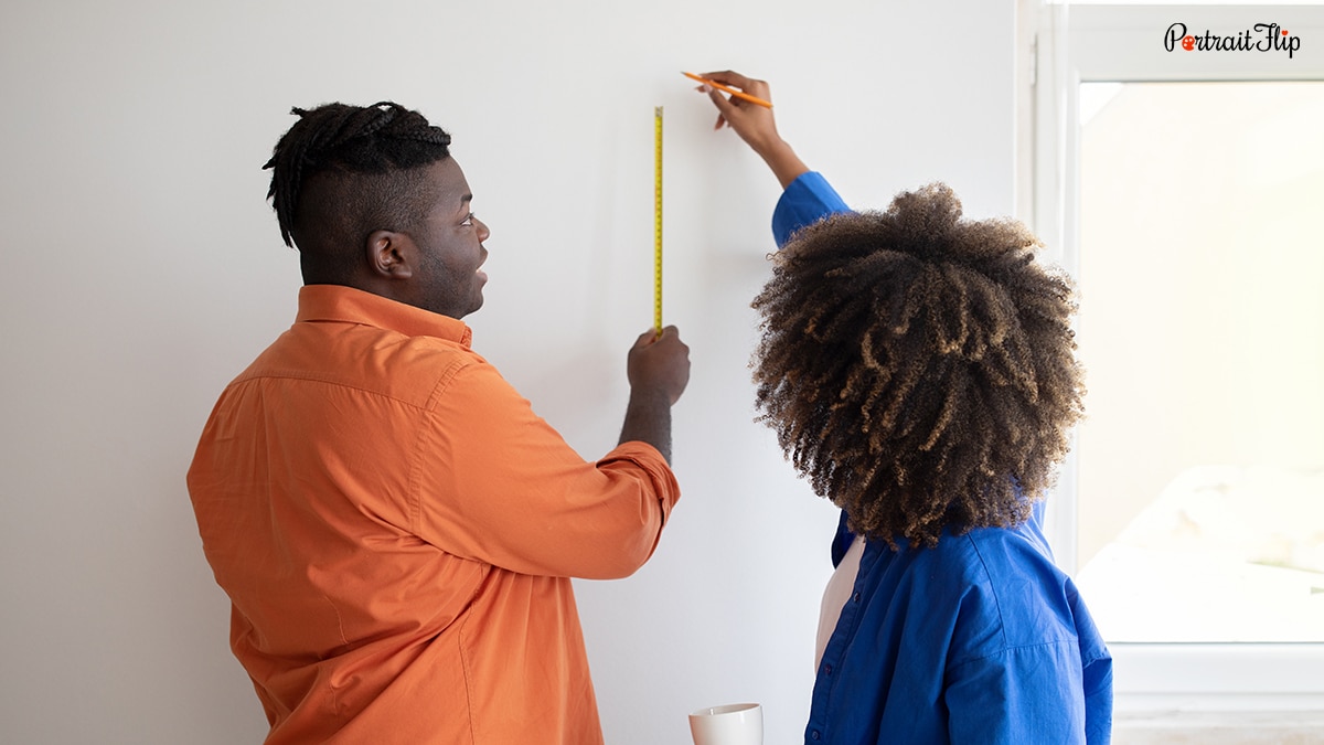 a couple measuring the height of the wall to order the canvas 