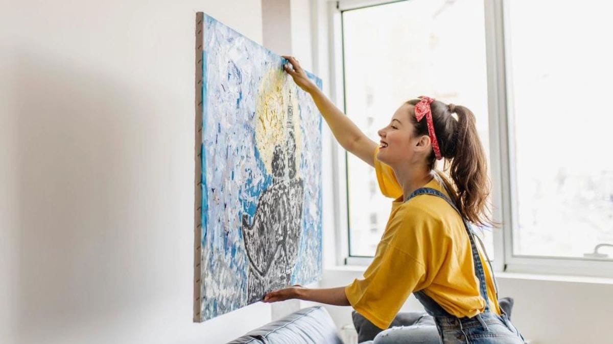  an art lover is mounting her oil painting back to the wall
