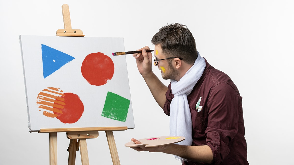 A man painting shapes on canvas
