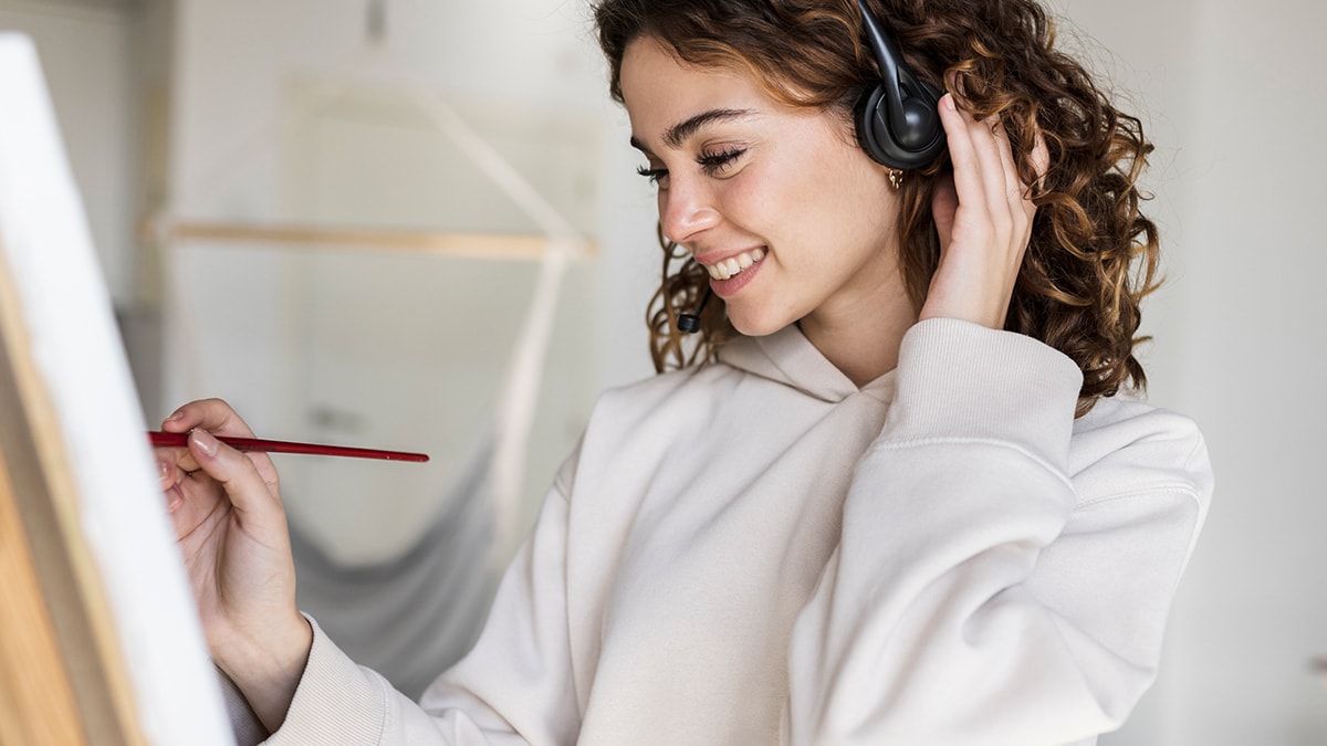 A girl wearing white sweatshirt smiling and laying the brush across the canvas