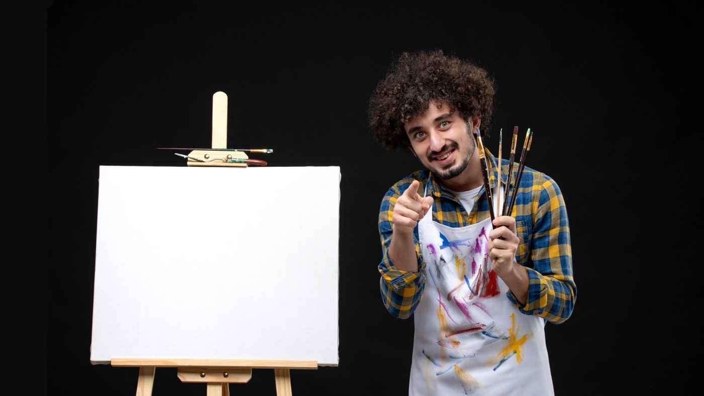 a live wedding painter smile and pointing his finger to the viewer