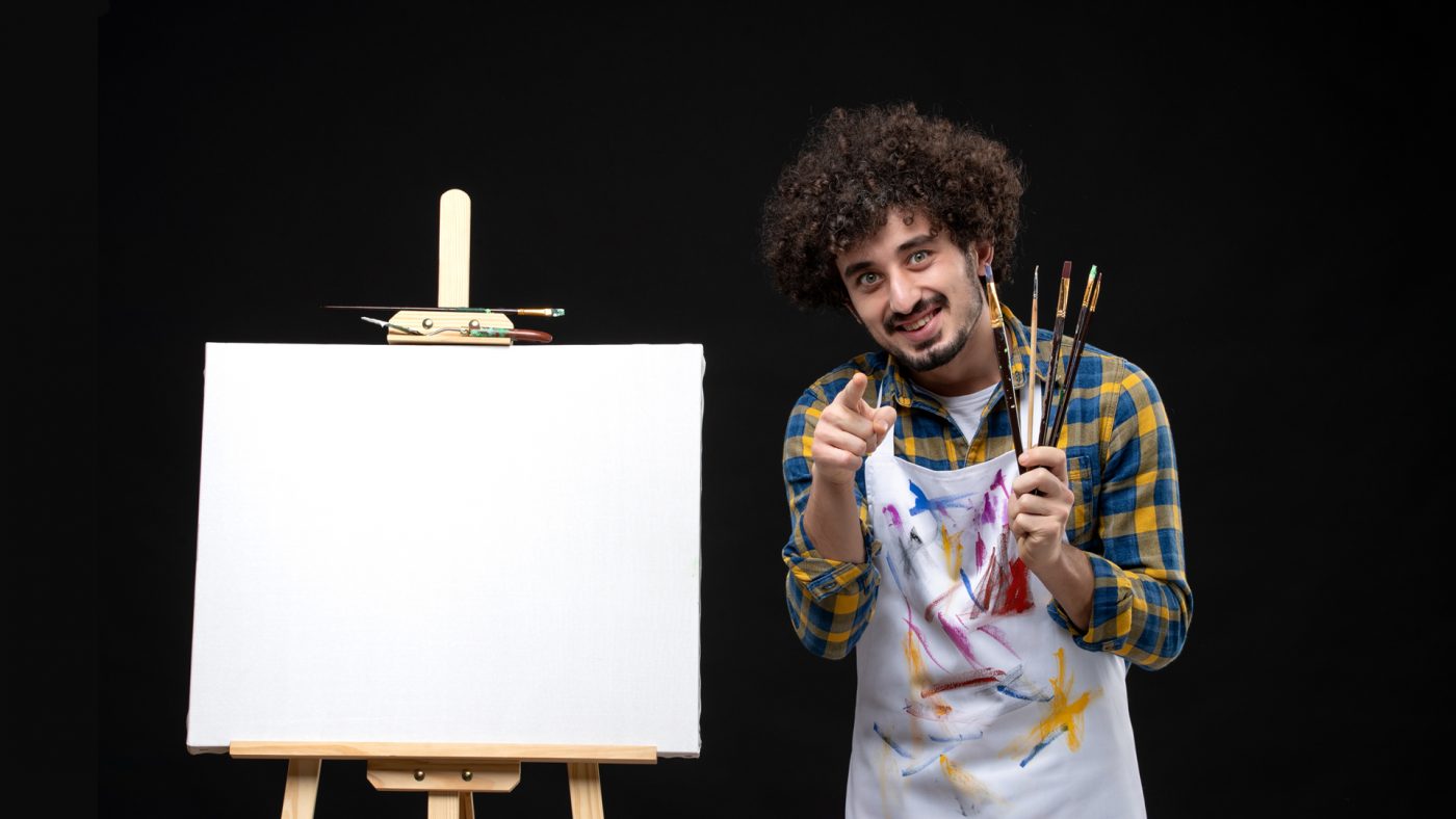 a live wedding painter smile and pointing his finger to the viewer 