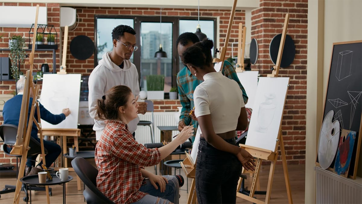 A group of artists discussing what's on the canvas