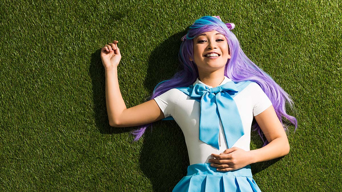 a girl lying on her back smiling at the viewer wearing a long shiny wig