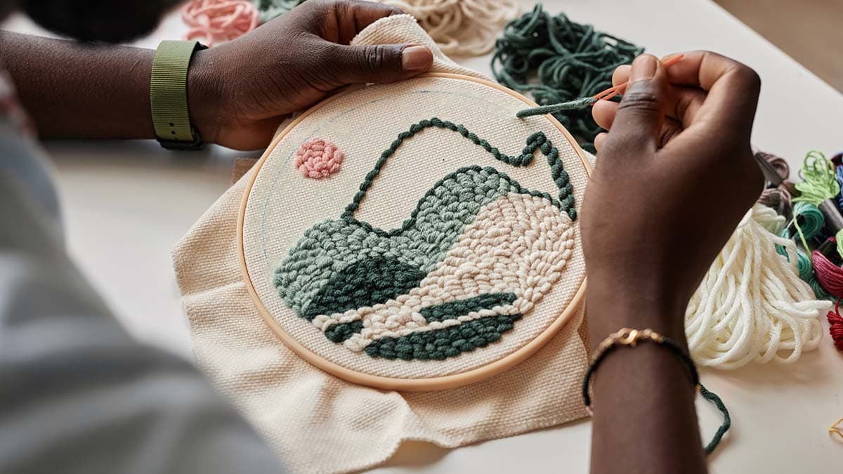 a guy sewing thread and creating a floral design